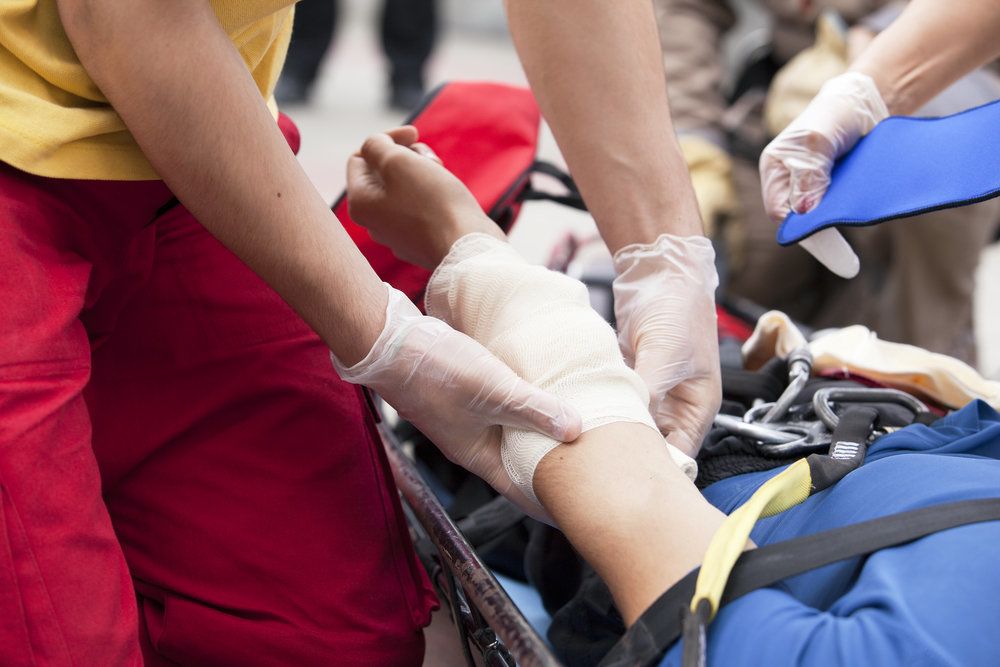 Man on stretcher receiving bandage on arm