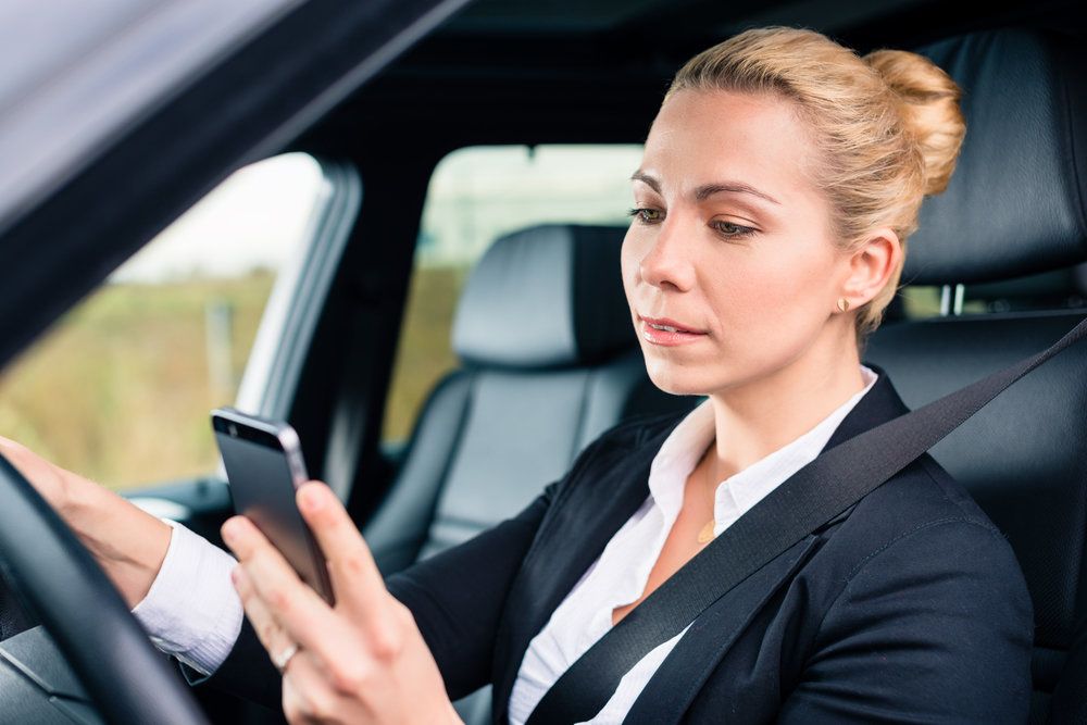 Woman driving and texting on her cell phone